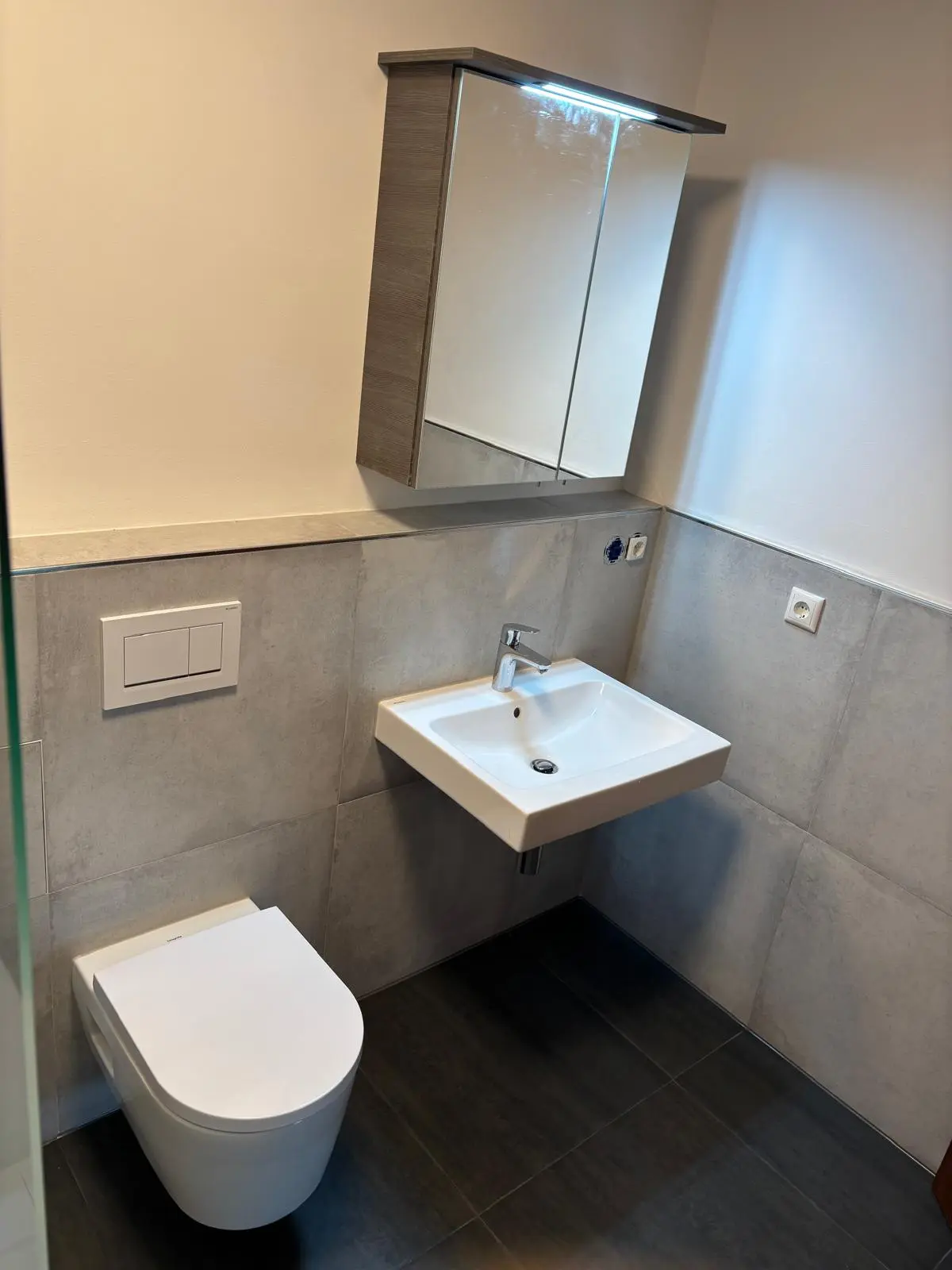 Fertiges Badezimmer: Funktionale Anordnung von WC, Waschbecken und Spiegelschrank – Joma Bau