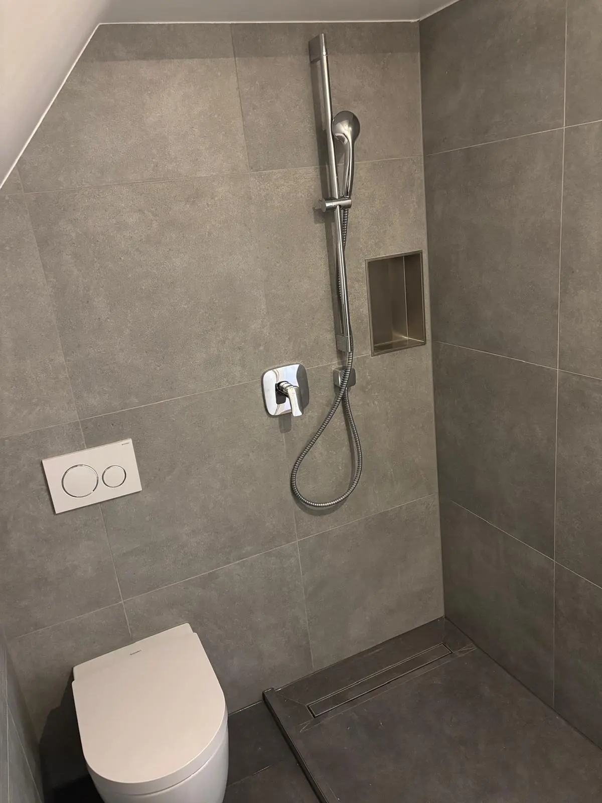 Kompaktes Badezimmer-Design: Bodengleiche Dusche mit Nische direkt neben dem WC – eine Platzspar-Lösung von Joma Bau