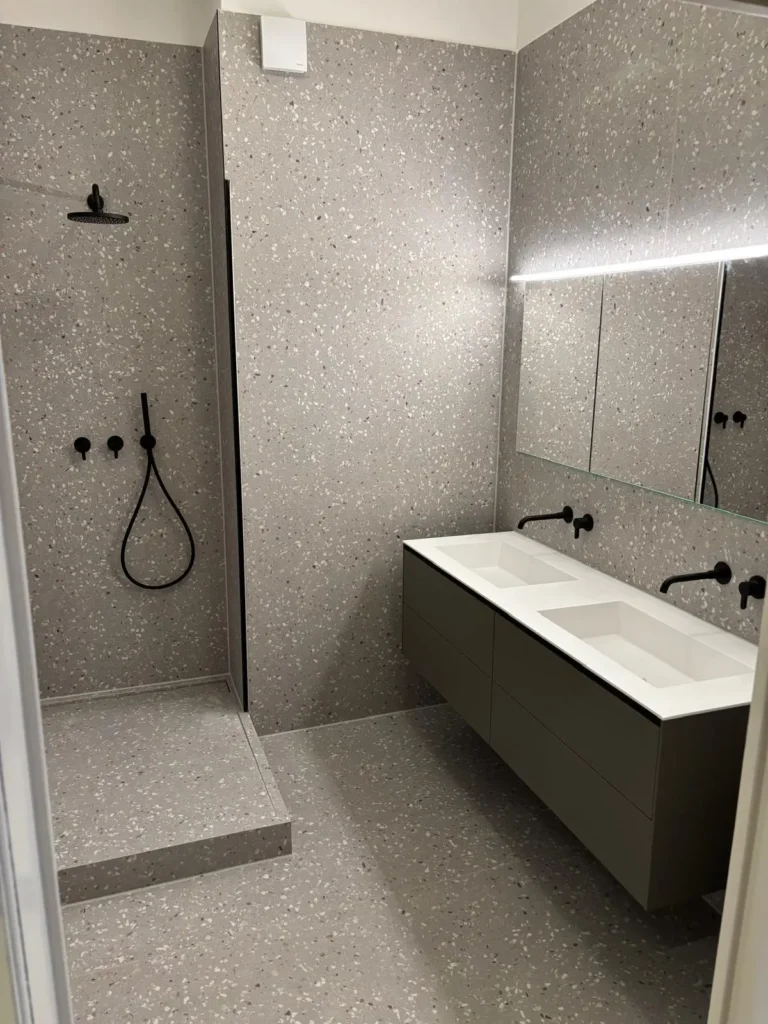 Joma Bau Badsanierung: Fertiggestelltes Premium-Bad mit mattschwarzen Unterputz-Armaturen, Regendusche und großem Spiegel mit LED-Beleuchtung