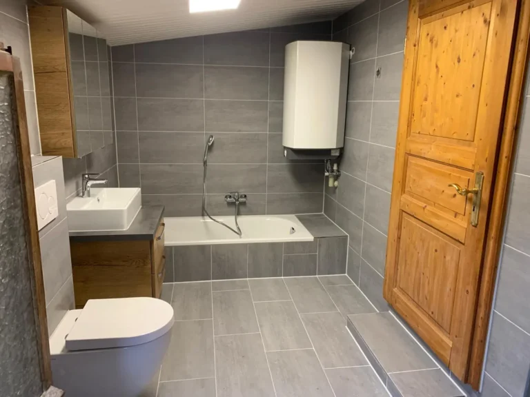 Clevere Raumnutzung: Saniertes Bad unter der Dachschräge mit Badewanne, kleiner Stufe im Eingangsbereich und integriertem Wandboiler by JoMa Bau - Badsanierung